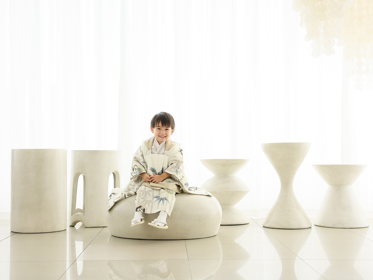 七五三の着物姿で白いスツールに座る男の子