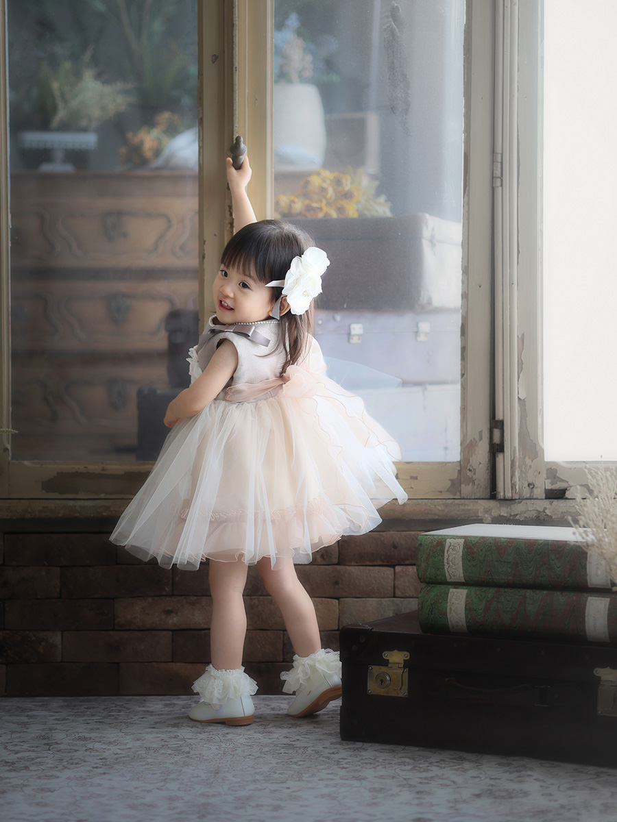ドレス姿で窓に手を伸ばす女の子